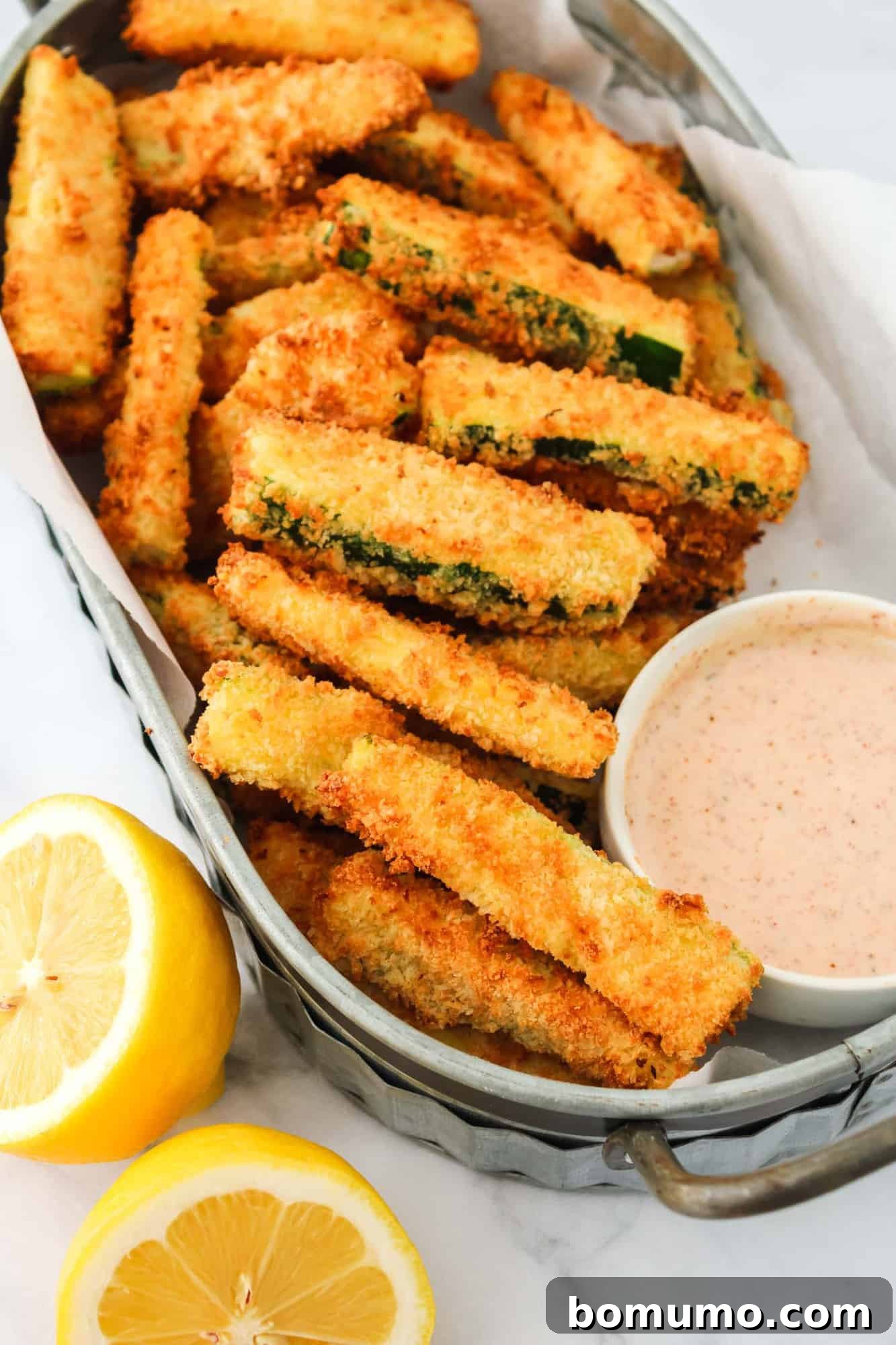 A large, overflowing basket of perfectly breaded zucchini fries, ready to be cooked or served.