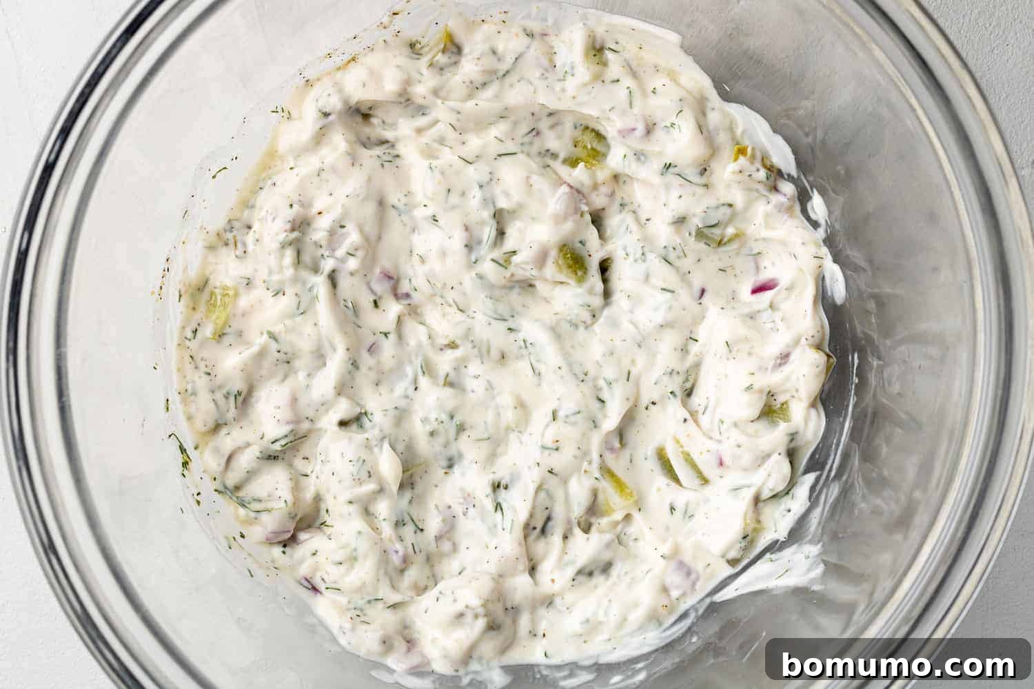 Tartar sauce completely combined and mixed together in a white mixing bowl, showing its creamy texture.
