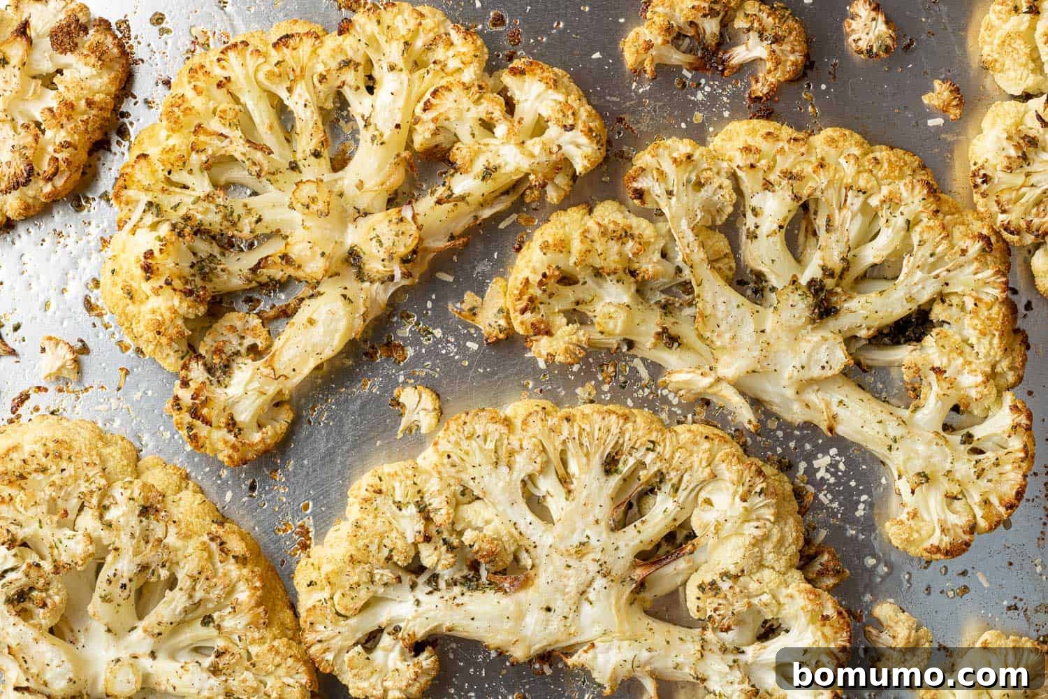 Beautifully roasted cauliflower slices with caramelized edges on a silver sheet pan, fresh out of the oven.