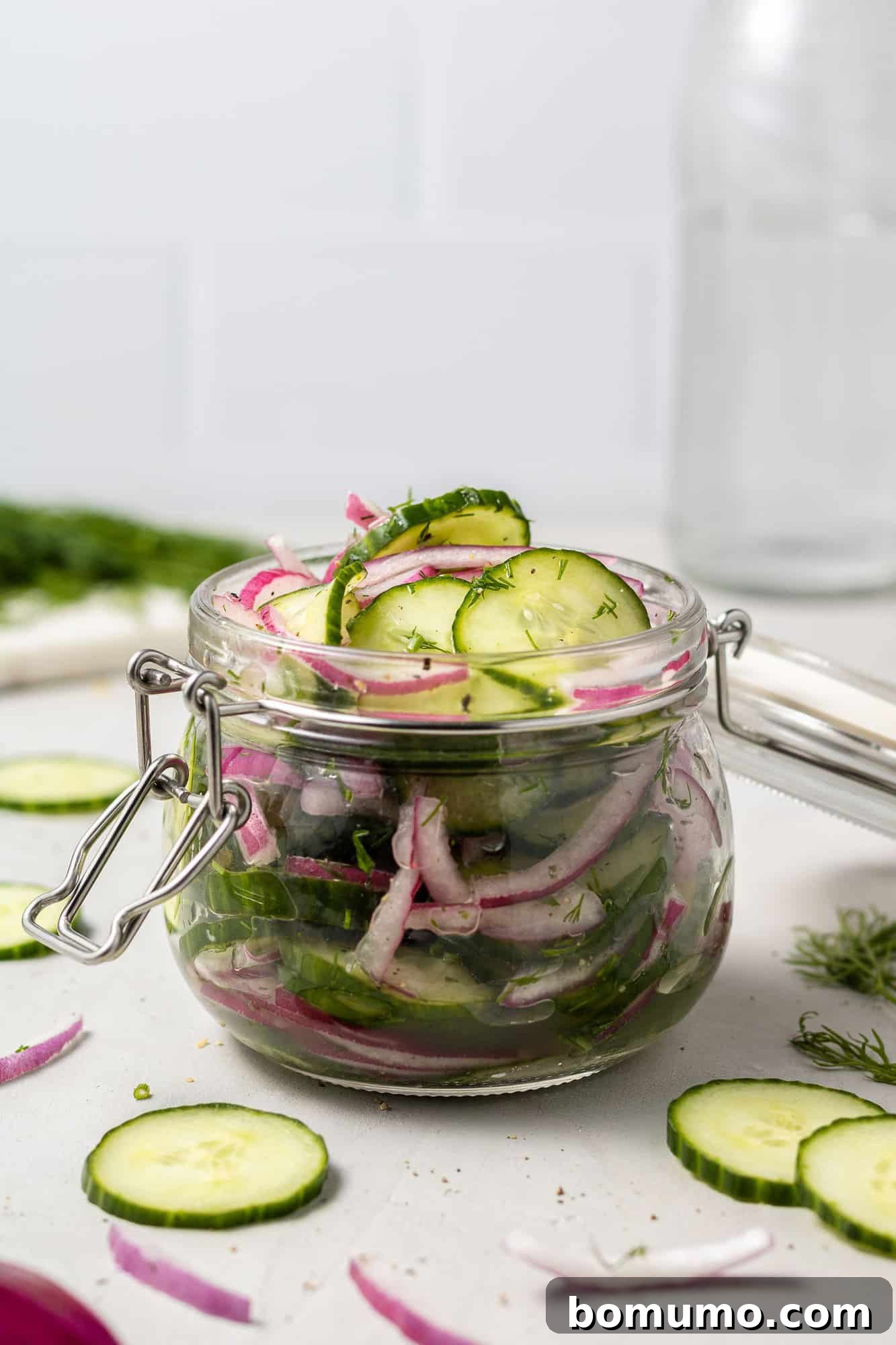Jar filled with sliced cucumbers and onions in a brine.