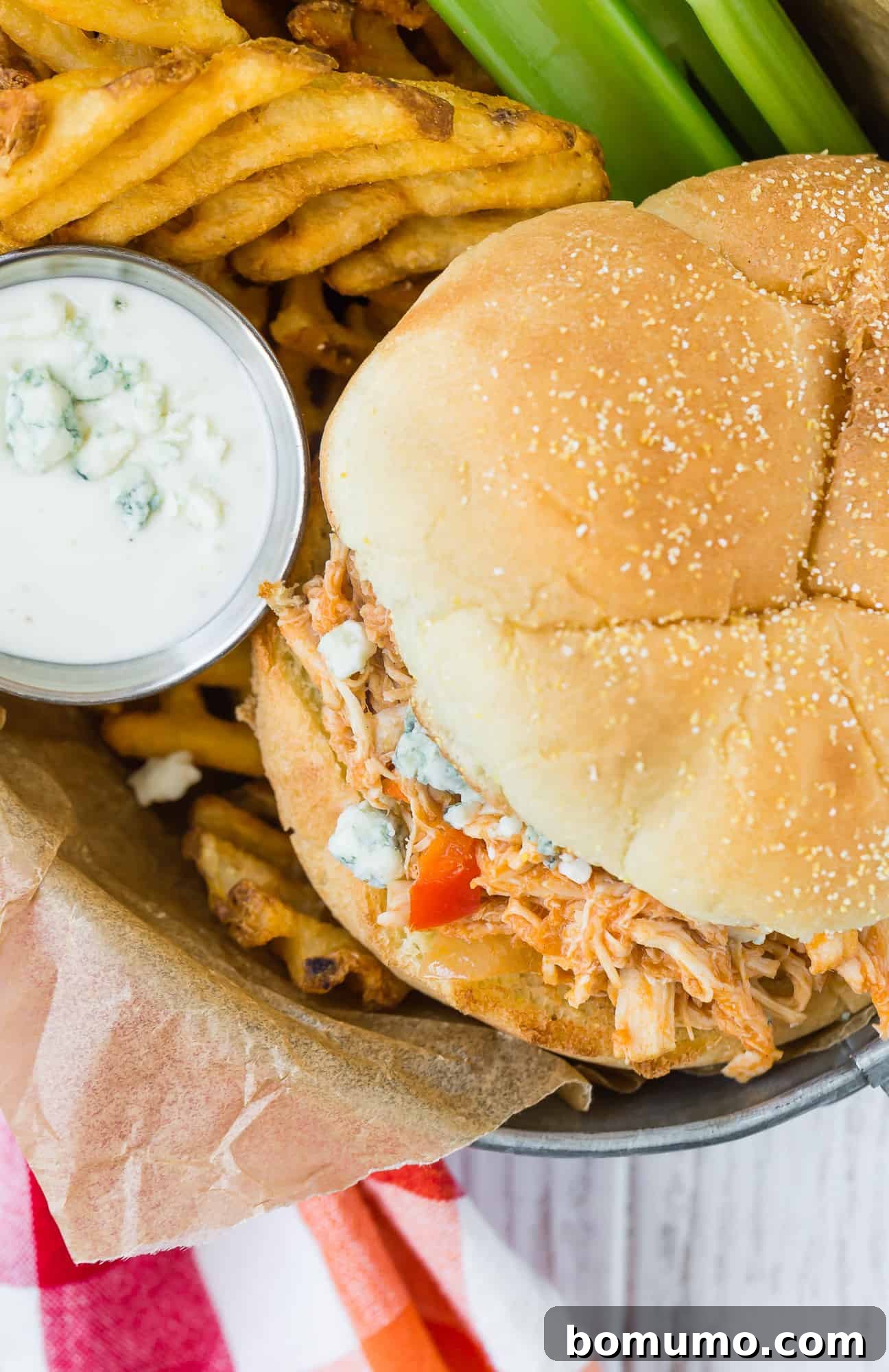 Overhead view of sandwich with fries and blue cheese dressing.