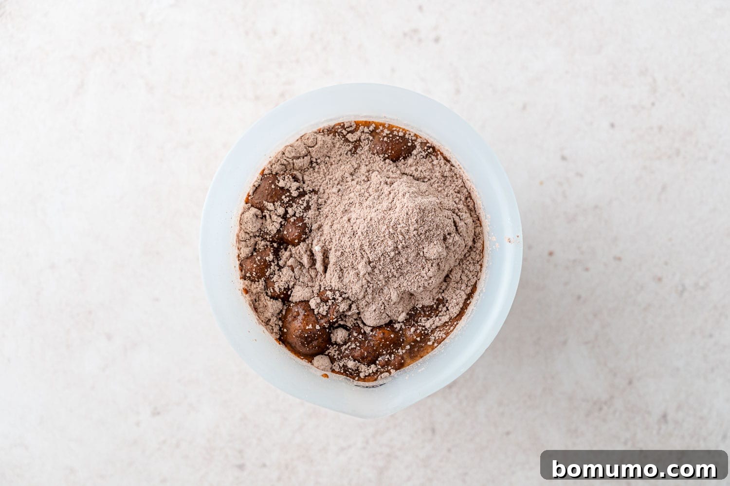 Instant pudding mix being added to a bowl of milk, prior to mixing for homemade pudding pops.