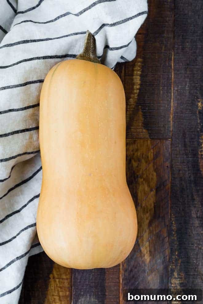 A whole, uncooked butternut squash resting on a wooden surface.