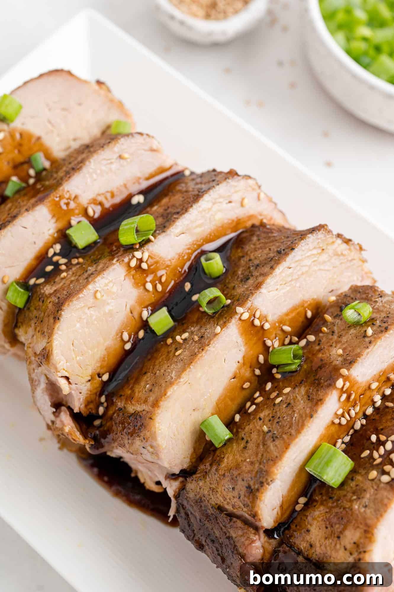 Slow cooker pork loin on a platter with balsamic glaze drizzled over.