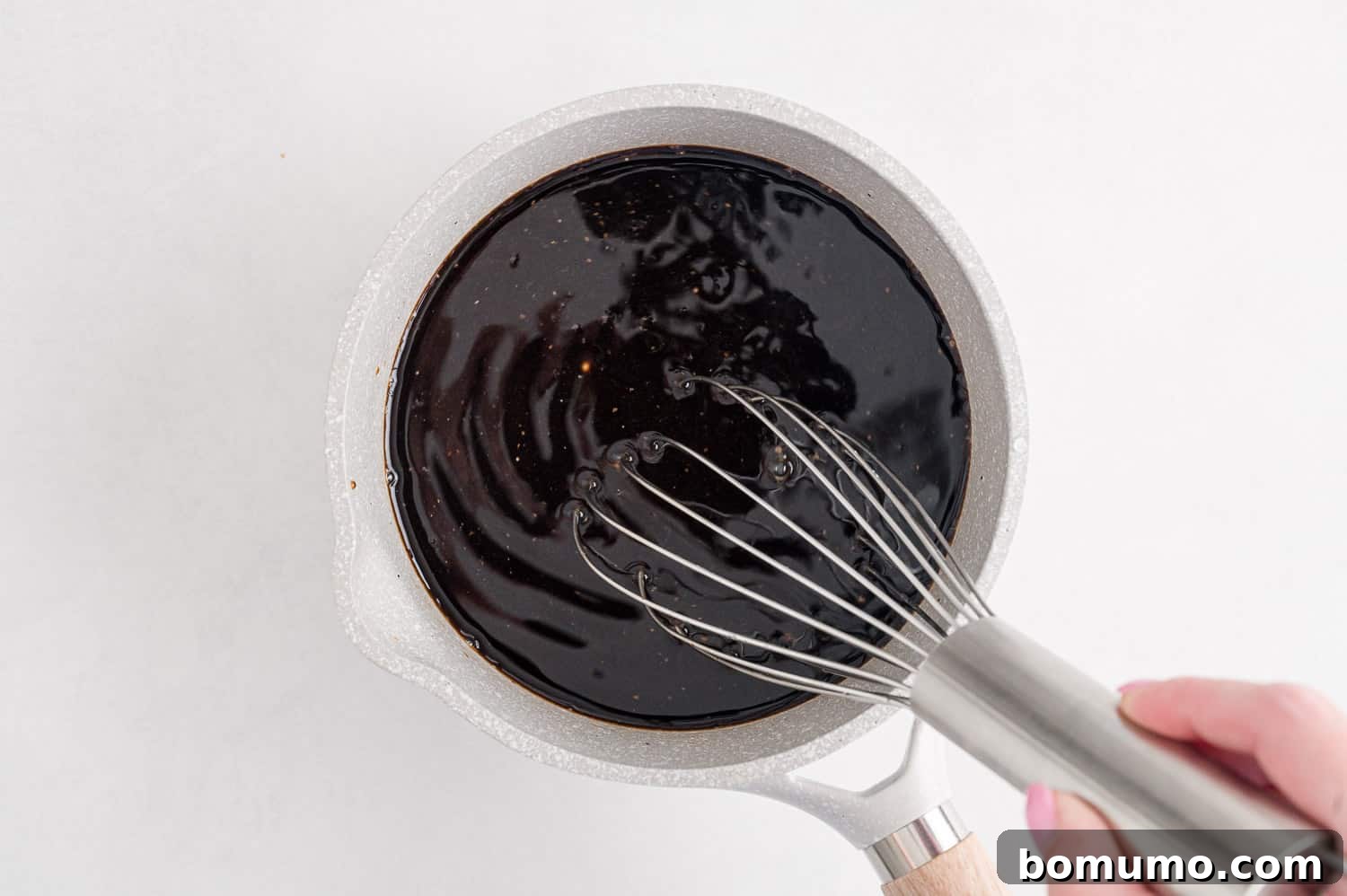 Balsamic glaze simmering in a small saucepan on the stove.