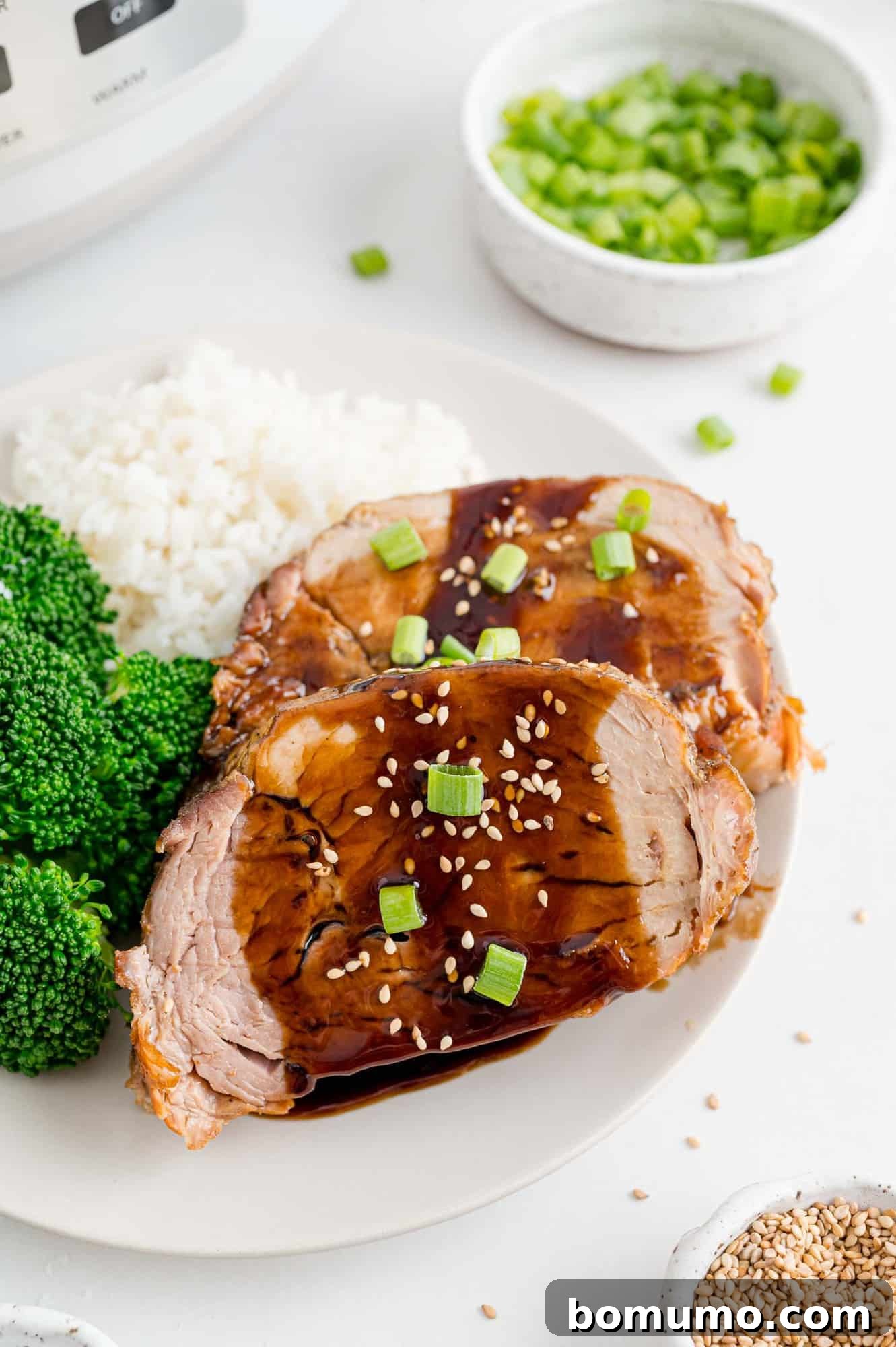 Sliced slow cooker pork loin with balsamic glaze, served with broccoli and rice.