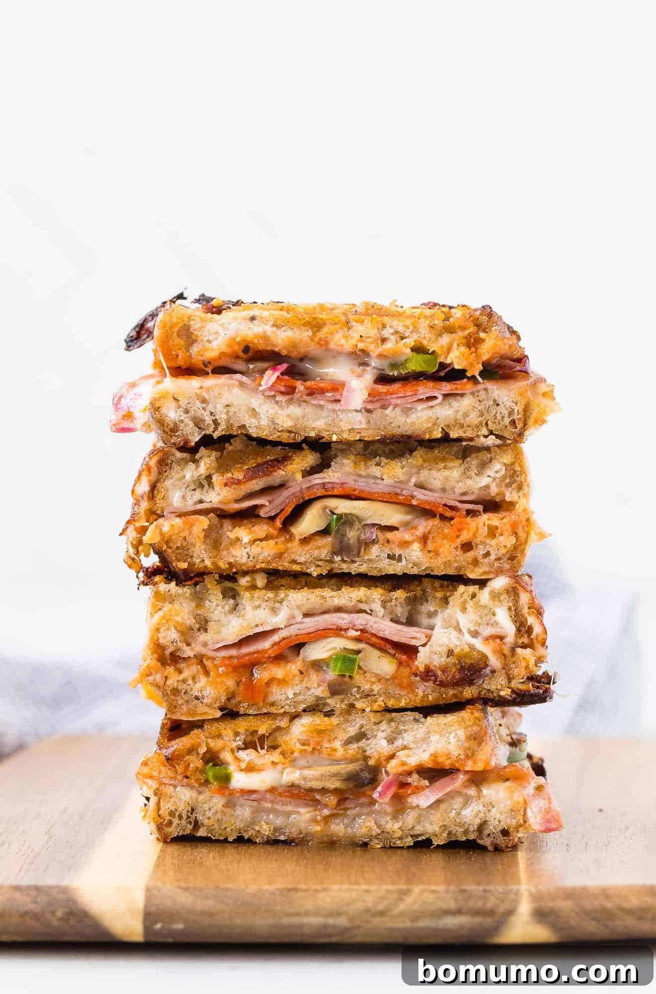 Grilled Pizza Panini 2 Stack of pizza paninis cut in half, revealing melted cheese and vibrant fillings.