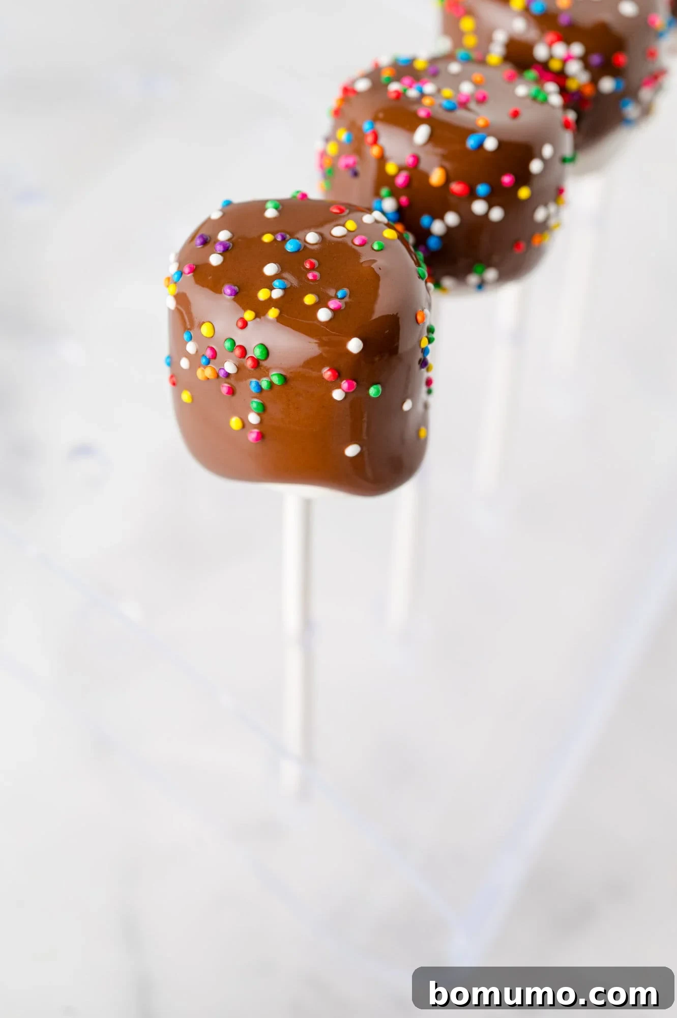 Velvet Dipped Mallows 13 A chocolate covered marshmallow being sprinkled with colorful jimmies.
