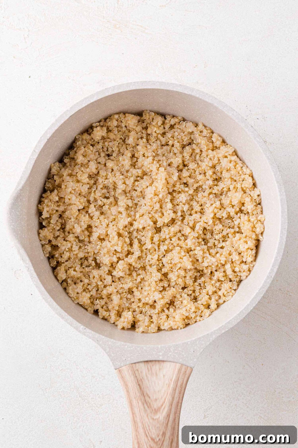 A saucepan filled with perfectly cooked, fluffy quinoa, reflecting its readiness as a nutritious base for the vibrant autumn salad.