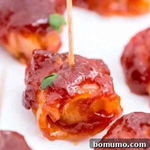 Close up of a water chestnut that is wrapped in bacon and covered in sauce, glistening and ready to eat.
