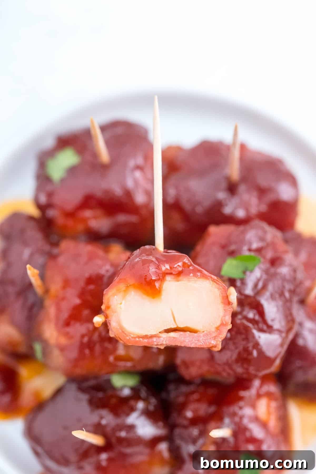 A single bacon-wrapped water chestnut, neatly cut in half, showcased atop a delicious pile of the full appetizers, each pierced with a toothpick.