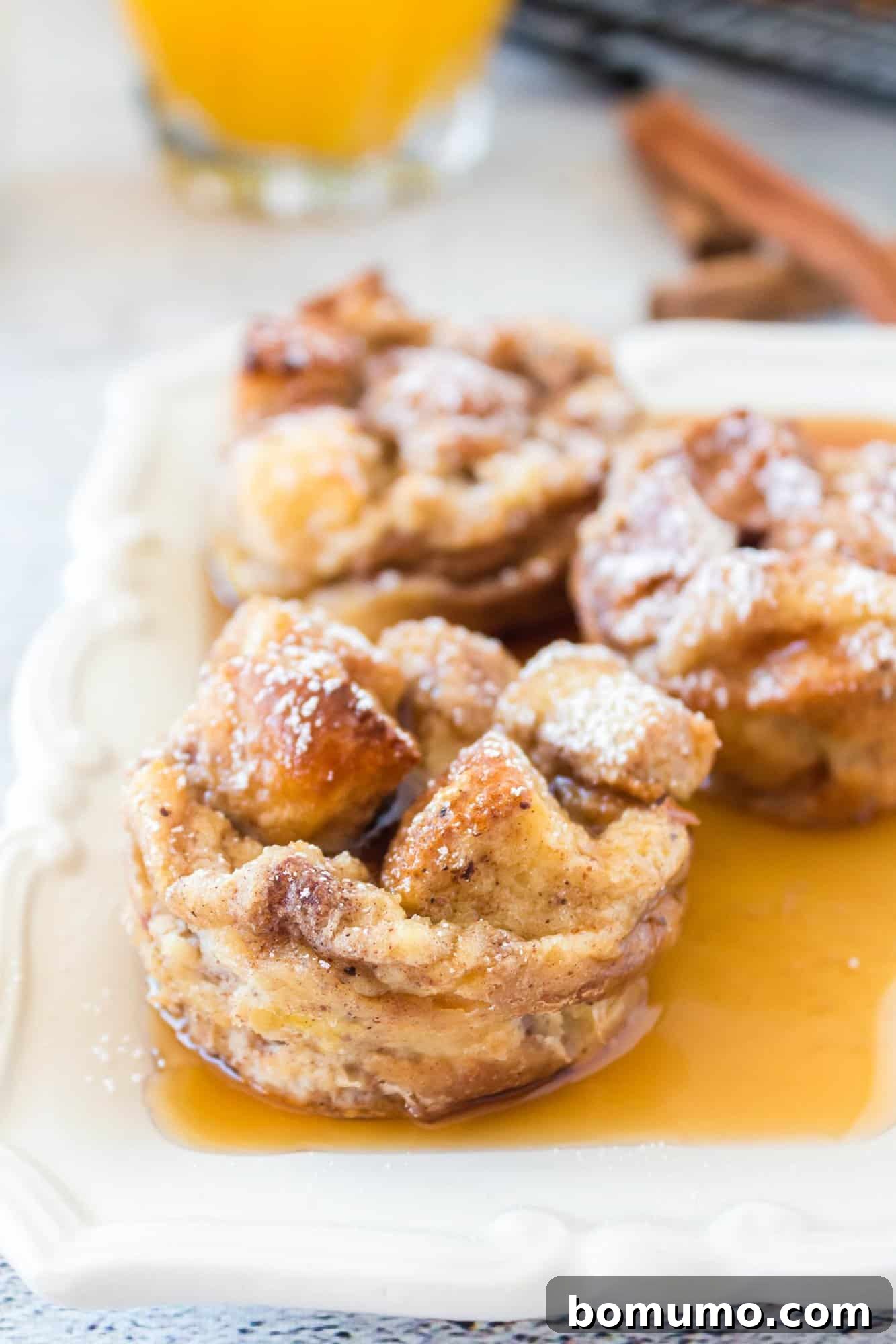 Golden French toast muffins drizzled with maple syrup and dusted with powdered sugar, ready to be enjoyed.