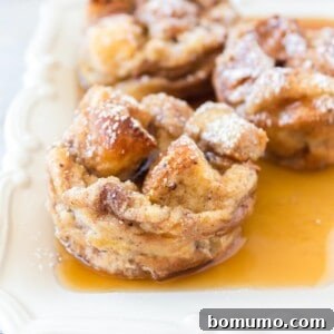 French toast muffins sprinkled with powdered sugar, in a pool of syrup.
