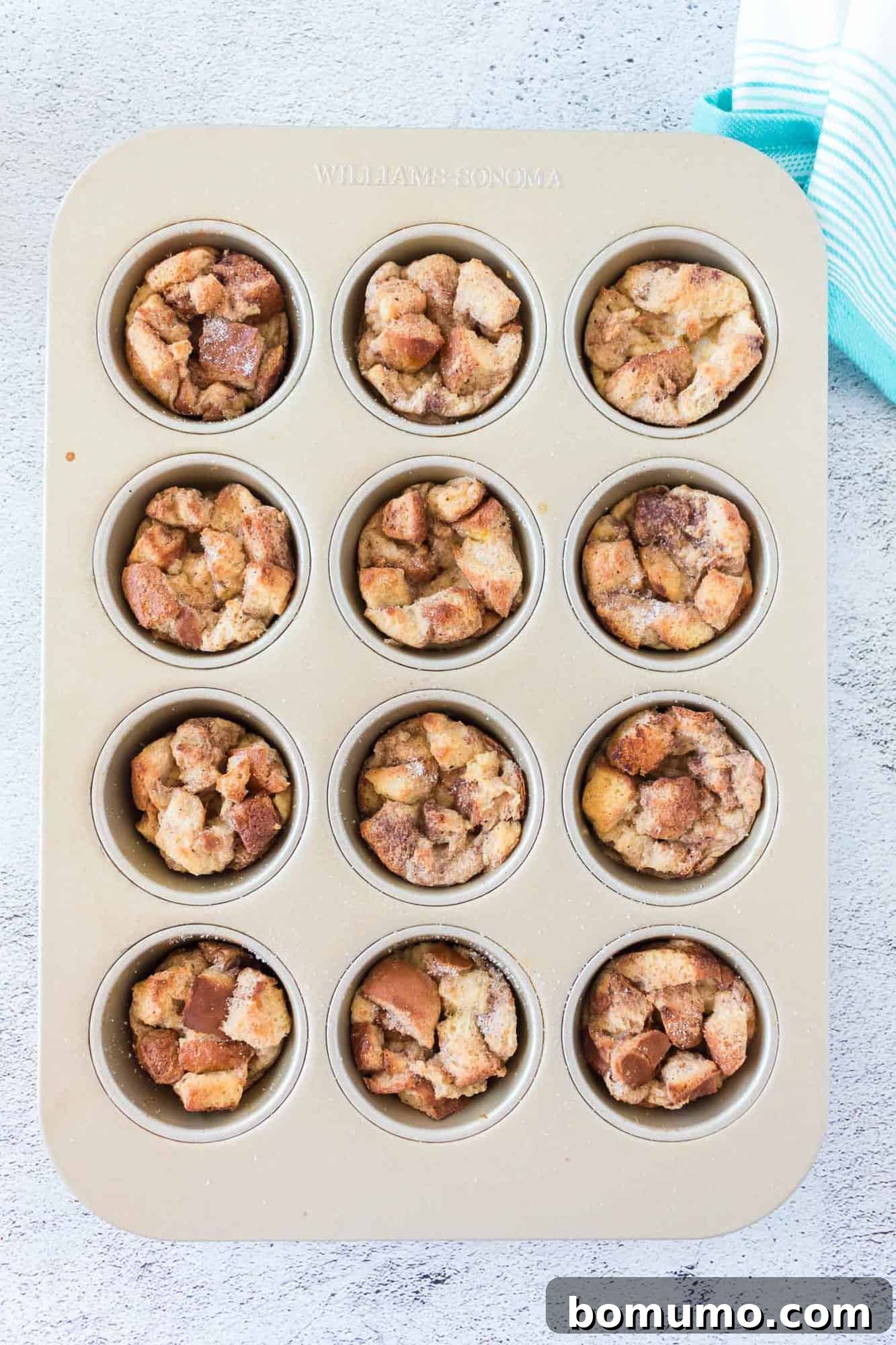 Freshly baked French toast muffins, still in their muffin tin, with golden brown tops.