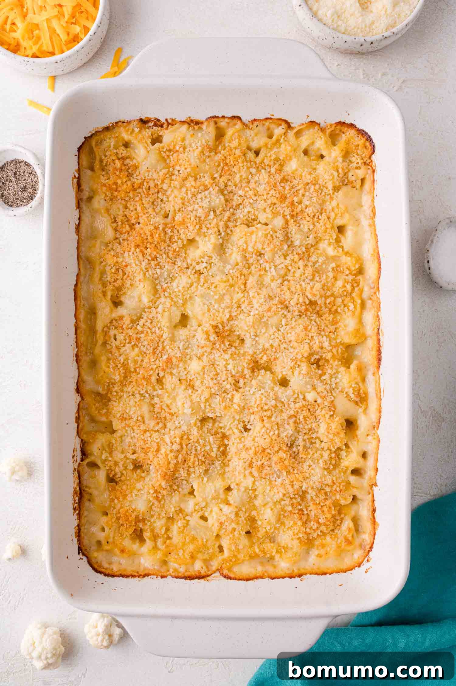 A freshly baked cauliflower and potato casserole with a perfectly golden, crispy breadcrumb topping, served in a white rectangular dish.