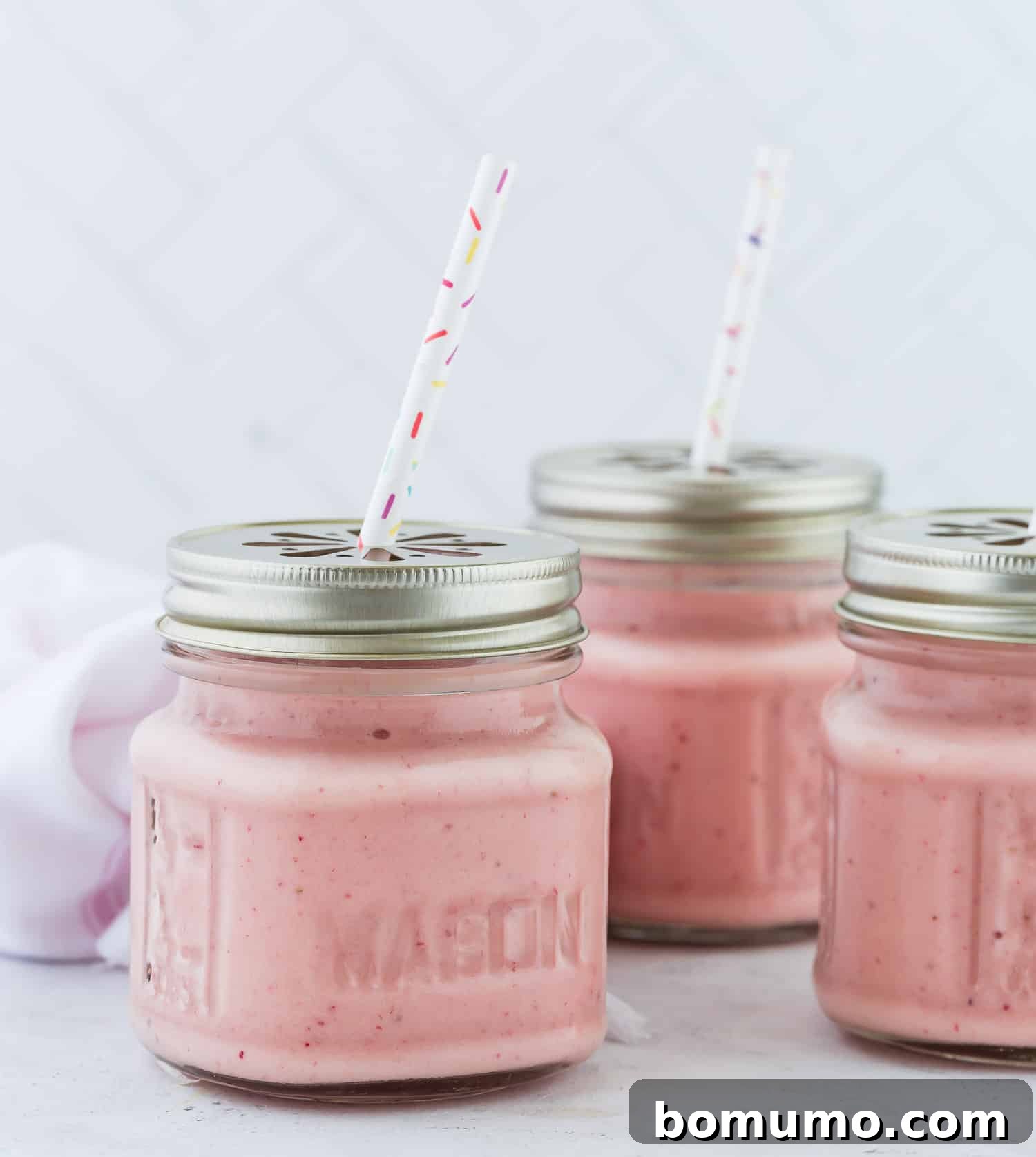 Island Escape Smoothie 3 Three tropical smoothies in small jars, garnished with lime wedges and fresh mint leaves.
