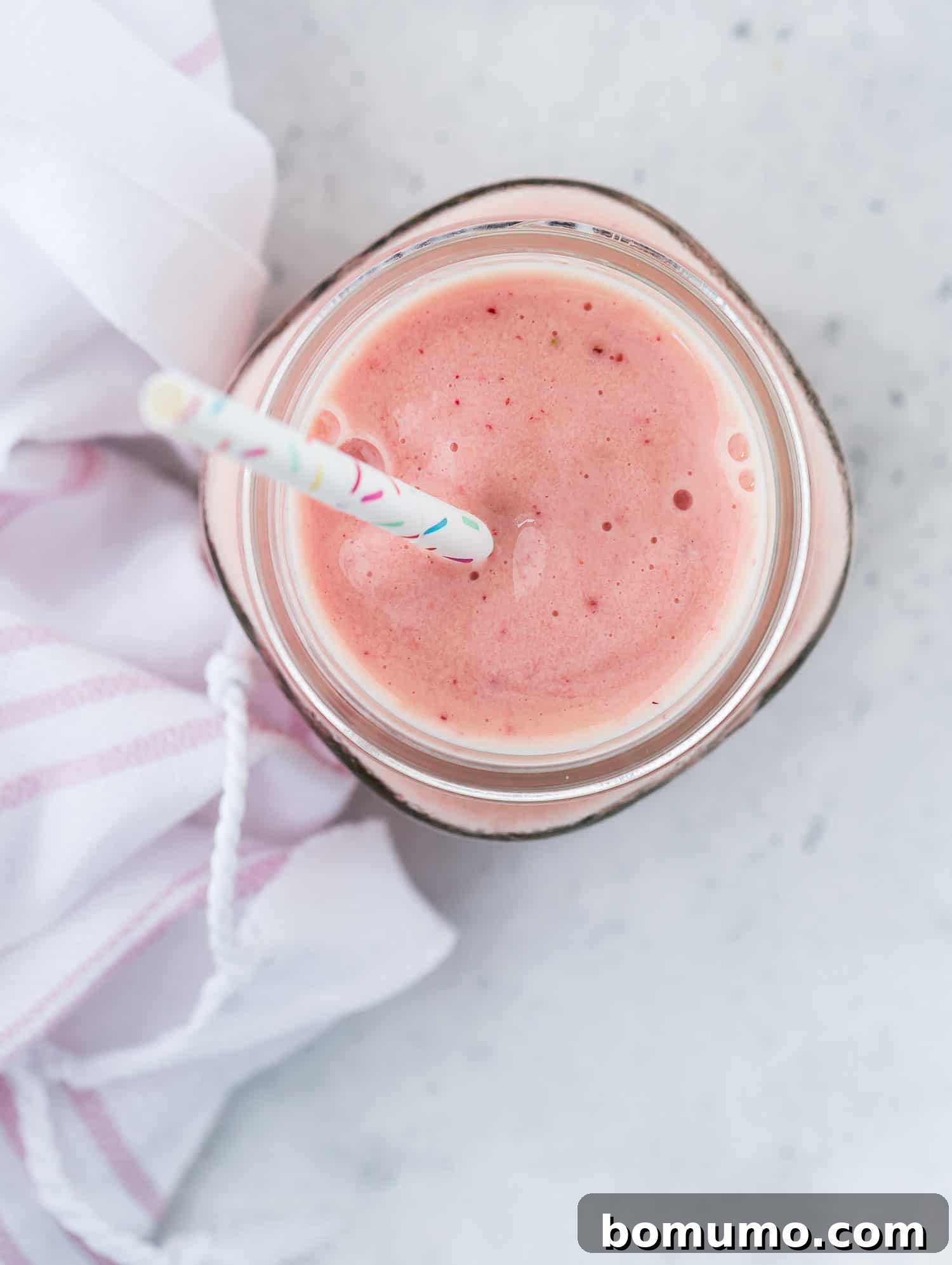 Island Escape Smoothie 4 Overhead view of a beautiful light pink tropical smoothie in a glass.