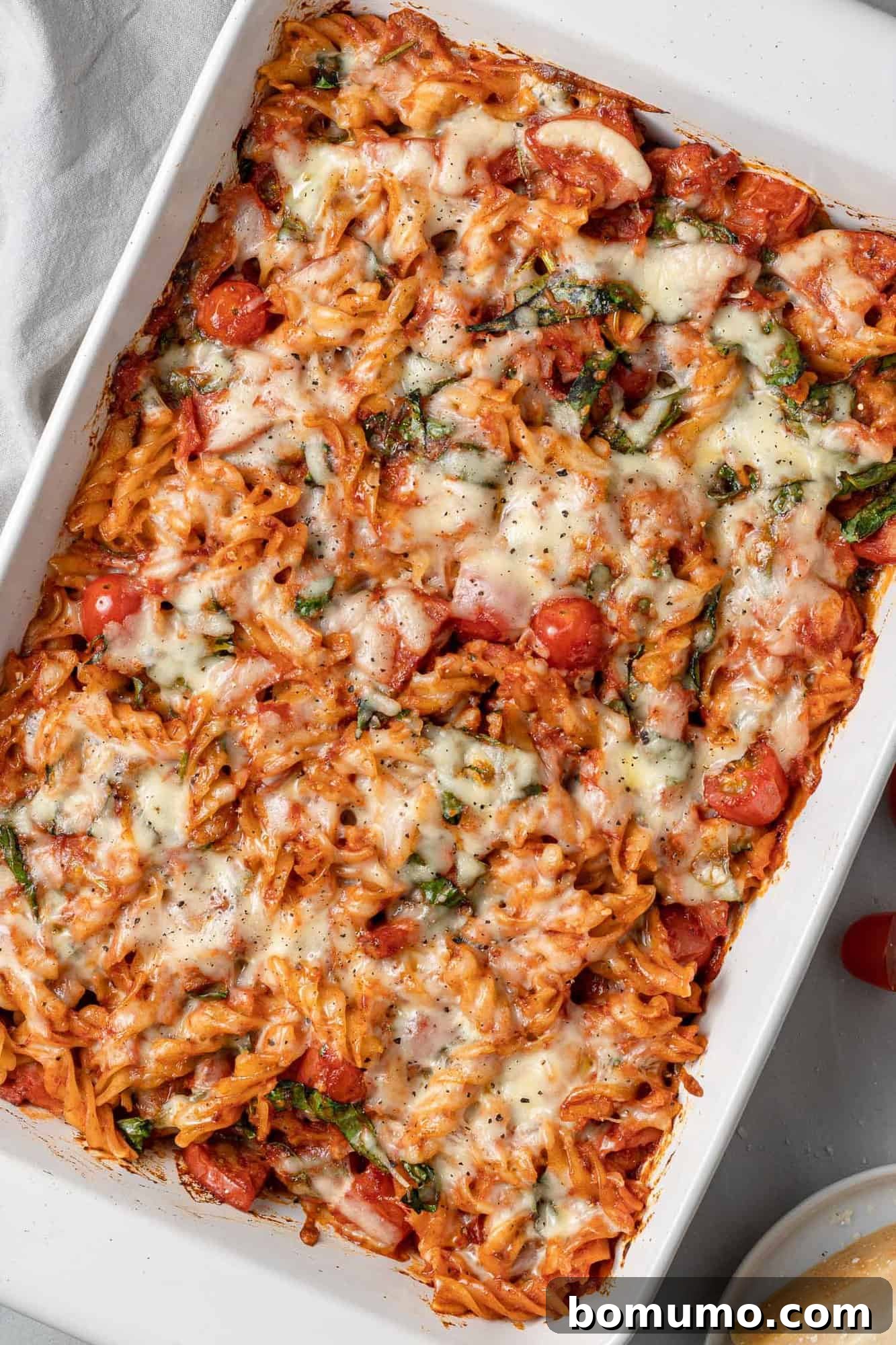 Overhead view of a golden-brown, bubbling pizza baked pasta casserole in a white baking dish, fresh out of the oven, ready to be served.