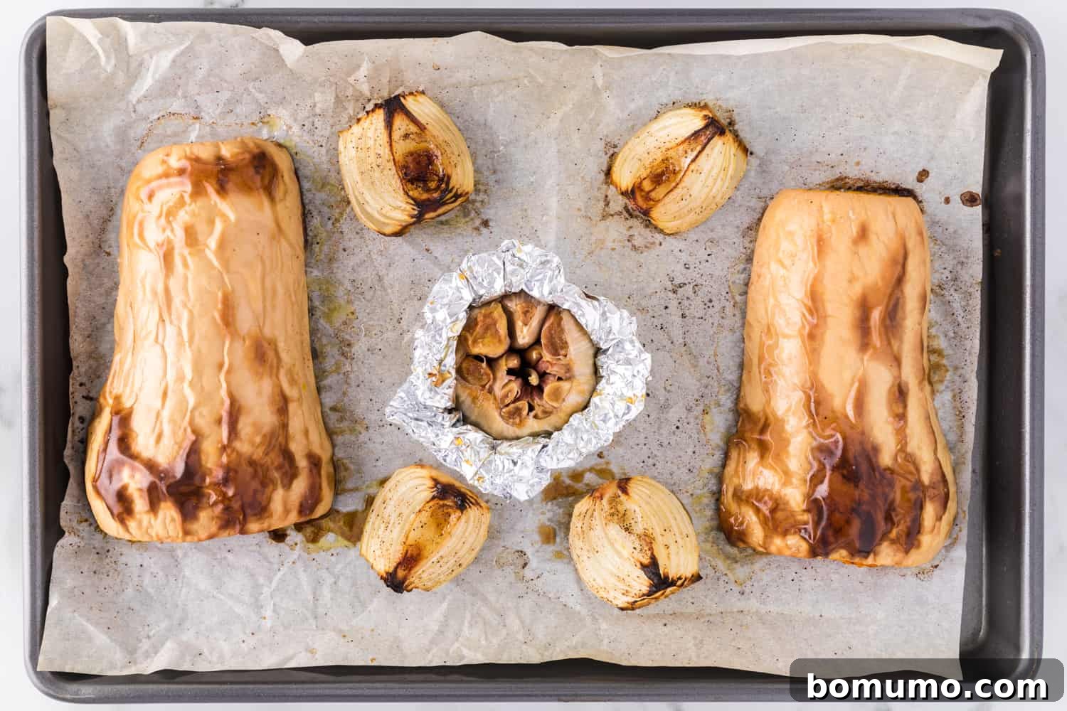 Roasted butternut squash, sweet onion, and garlic, fresh out of the oven and beautifully caramelized on a baking sheet.