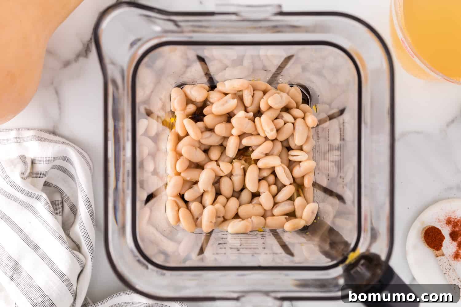 Rinsed white beans being added to the blender with the roasted vegetables and broth.