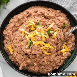 Crockpot refried beans in a large black bowl, ready to be served or stored.