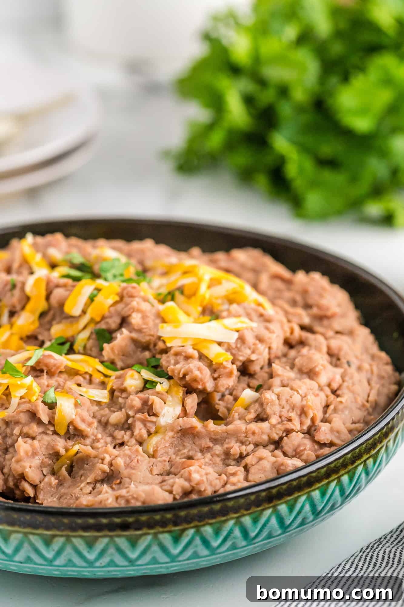 Close-up of perfectly cooked pinto beans in a rustic blue and black bowl, showcasing their tender texture.
