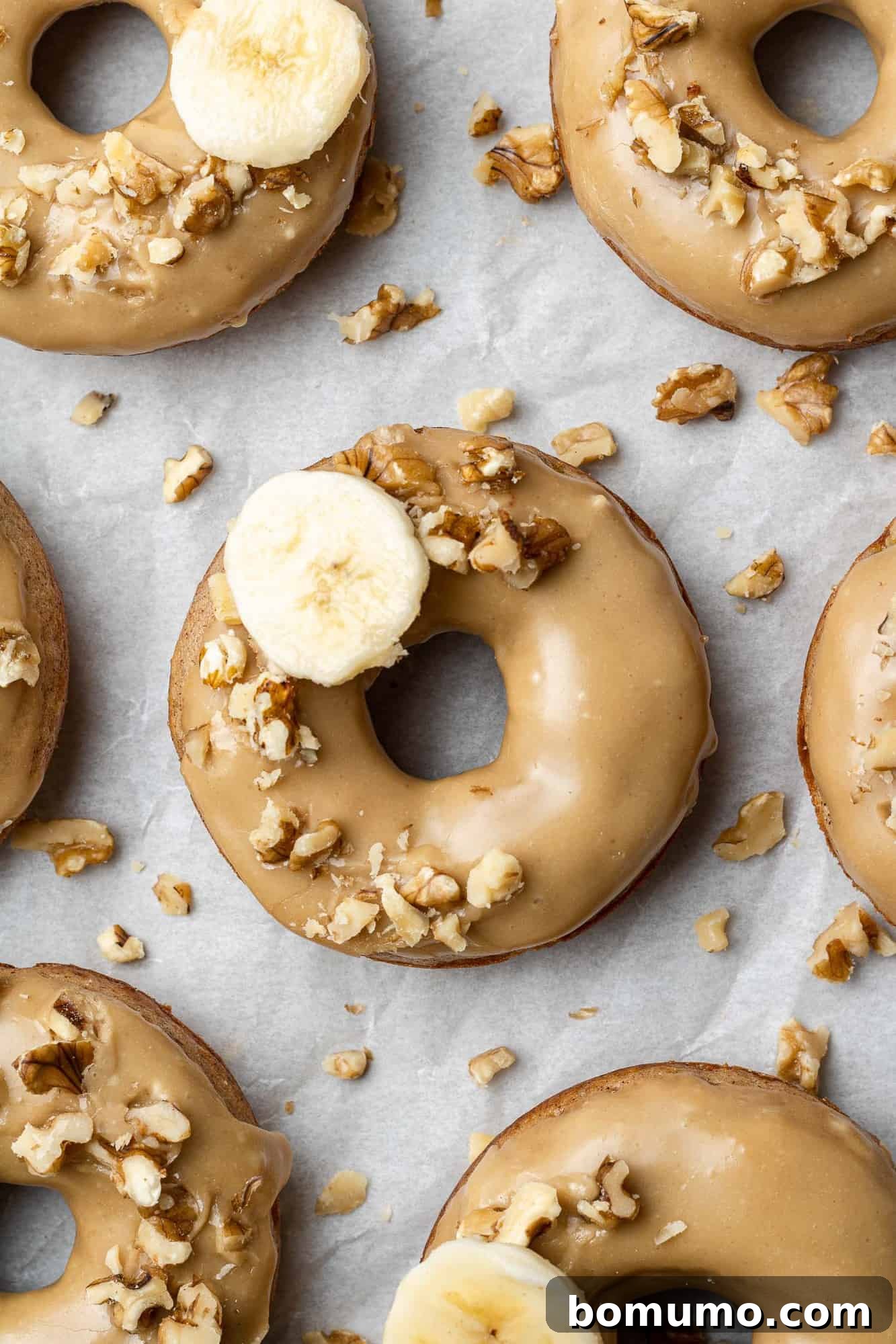 Delicious baked banana donuts with a brown sugar glaze and a sprinkle of walnuts.
