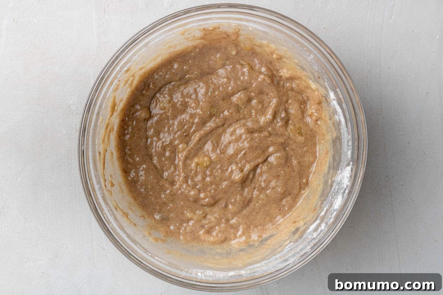 Close up of donut batter in a clear bowl, ready to be baked.