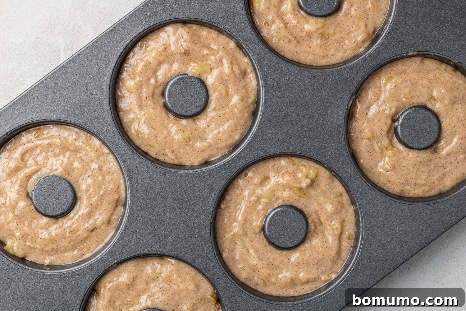 Unbaked donut batter in a donut pan, prepared for the oven.