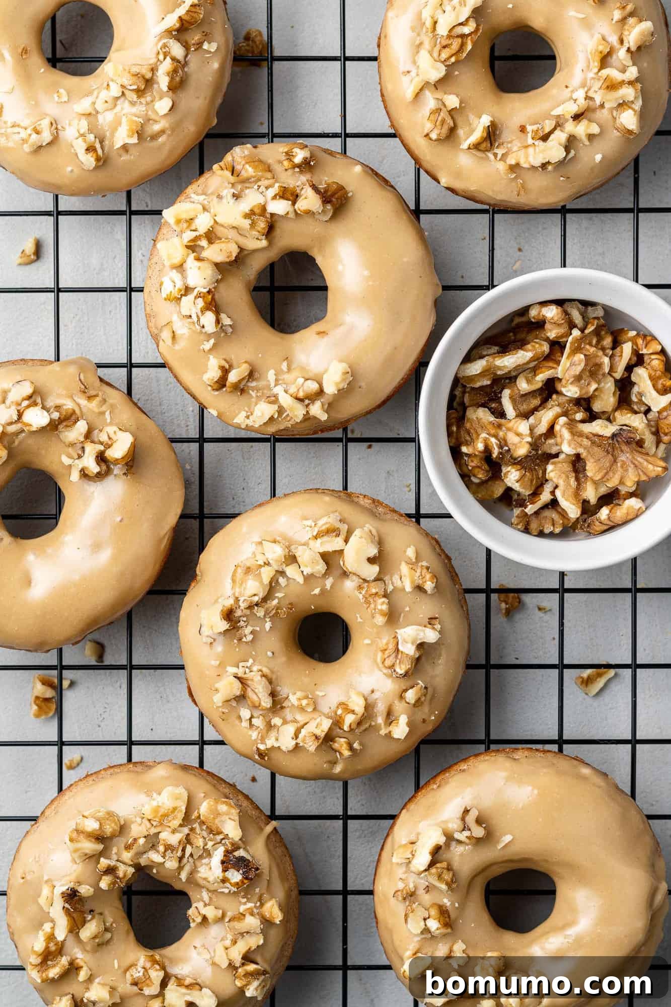 Glazed baked banana donuts topped with chopped nuts, ready to enjoy.