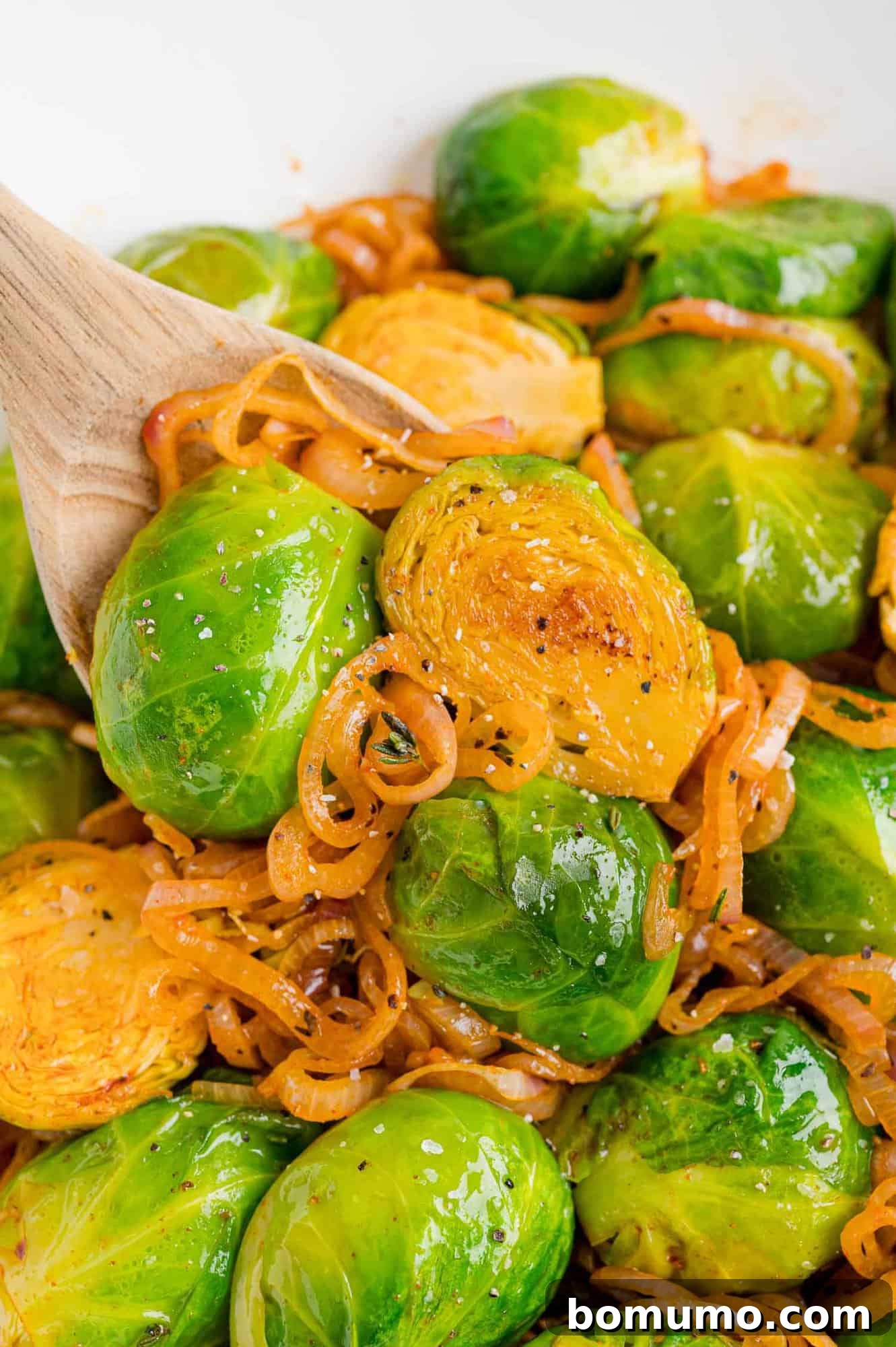 A wooden spoon serving smoky Brussels sprouts with shallots, highlighting the rich colors and textures.