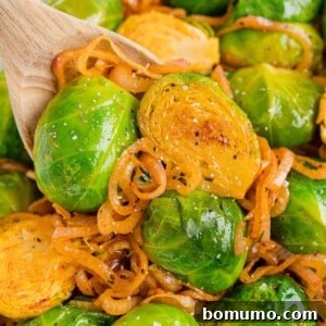 Smoky Brussels sprouts with shallots, presented beautifully on a wooden spoon.