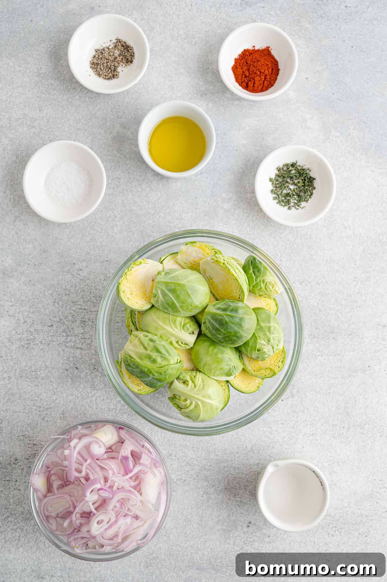 All the fresh ingredients laid out for making smoky Brussels sprouts: Brussels sprouts, shallots, olive oil, smoked paprika, and thyme.