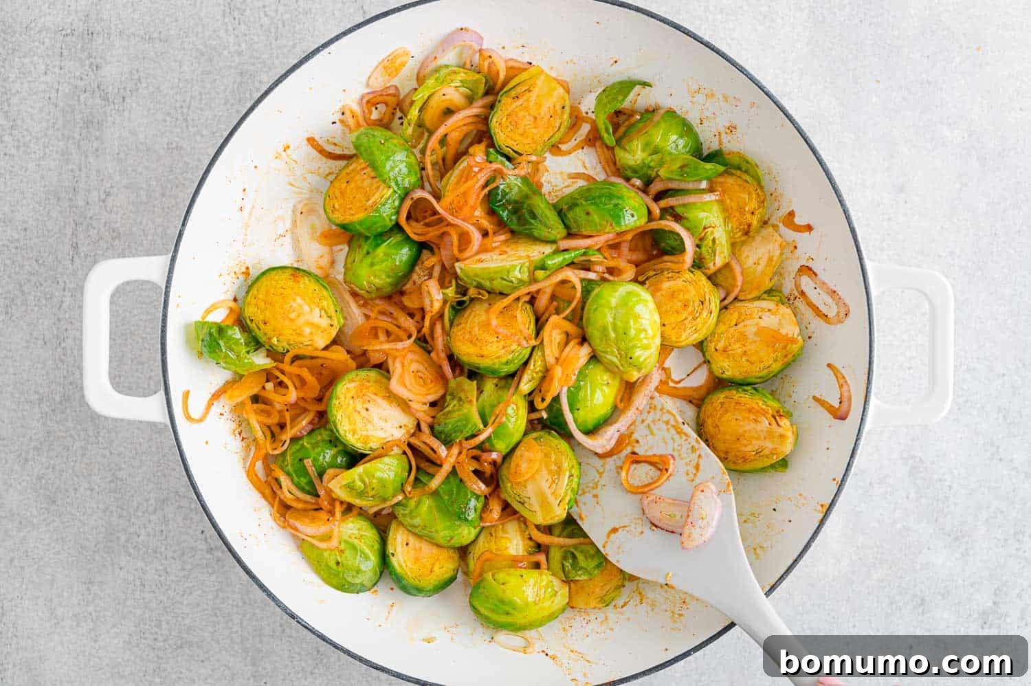 Brussels sprouts mixed thoroughly with smoked paprika and shallots, continuing to sauté in the skillet.