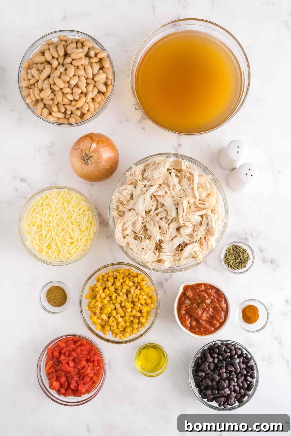 Overhead view of ingredients needed for white chili, all in glass bowls.