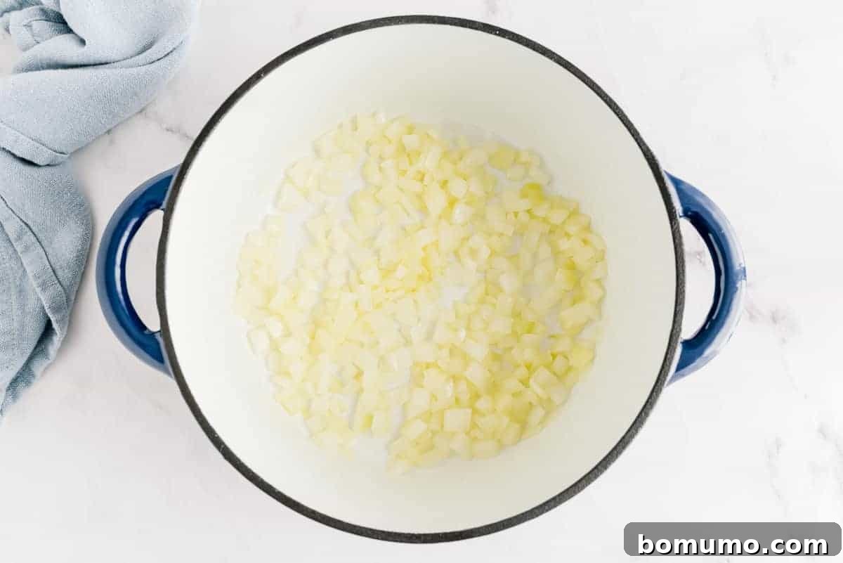 Onions cooking in oil in a blue and white pot.