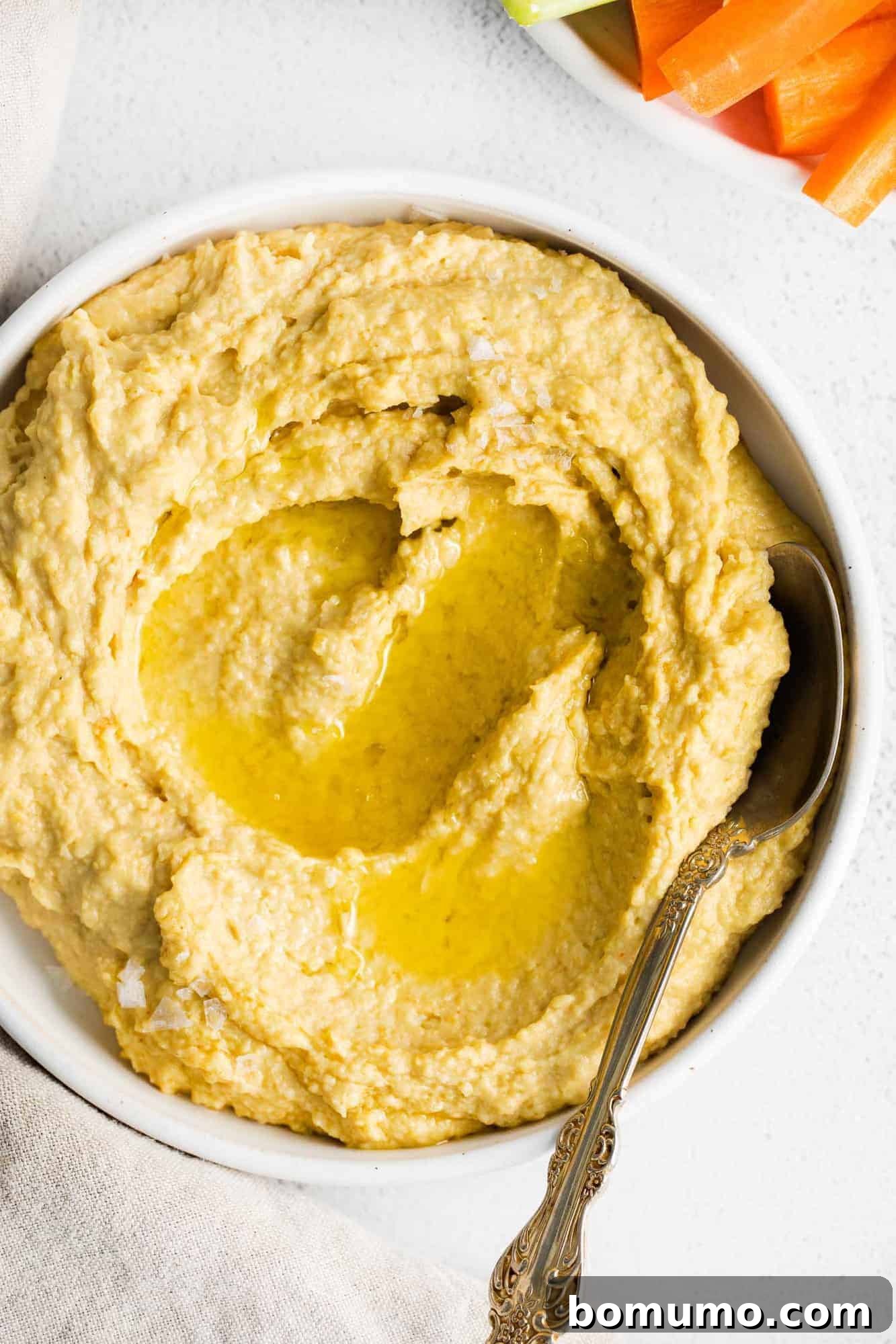 Hummus in a bowl topped with olive oil and spices, ready to be served as a healthy snack.