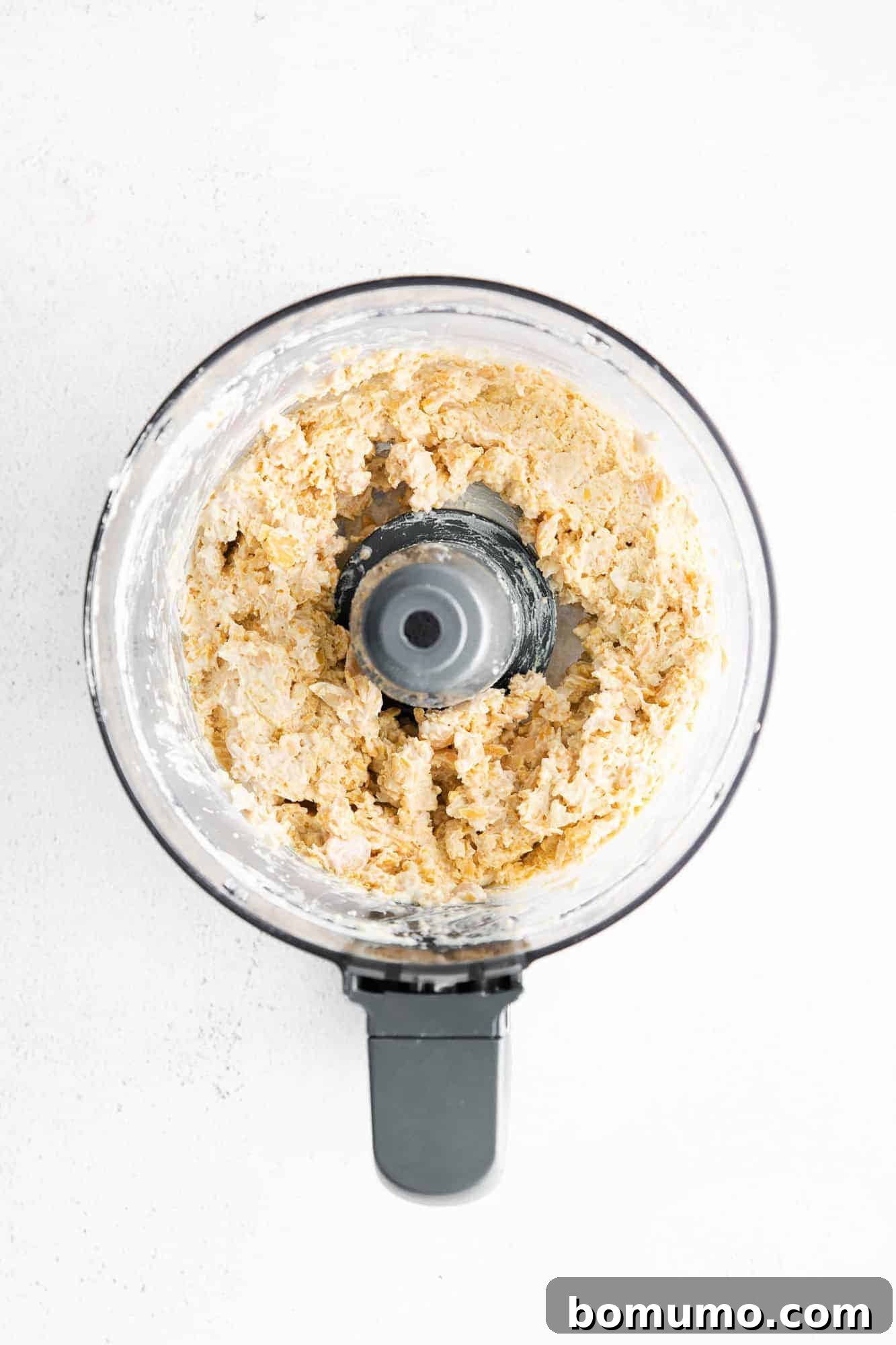 Chopped chickpeas and garlic in a food processor, demonstrating the initial stage of blending before olive oil is added for a smooth hummus texture.