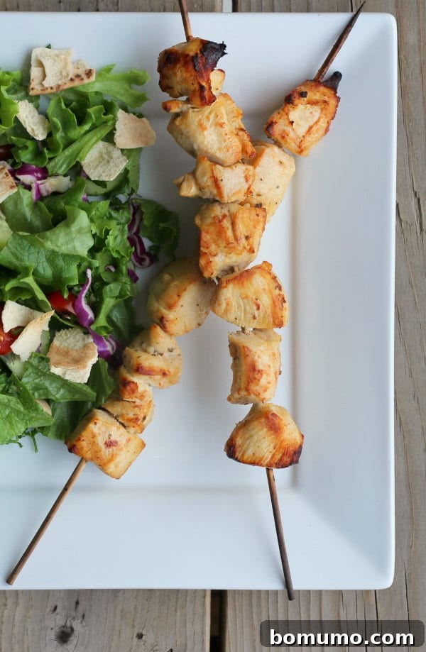 Partial overhead of skewers and salad on white plate.