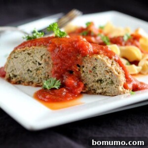 Serving of heart-healthy Italian Turkey Quinoa Meatloaf on white plate with whole grain noodles and marinara sauce, ready to be enjoyed.