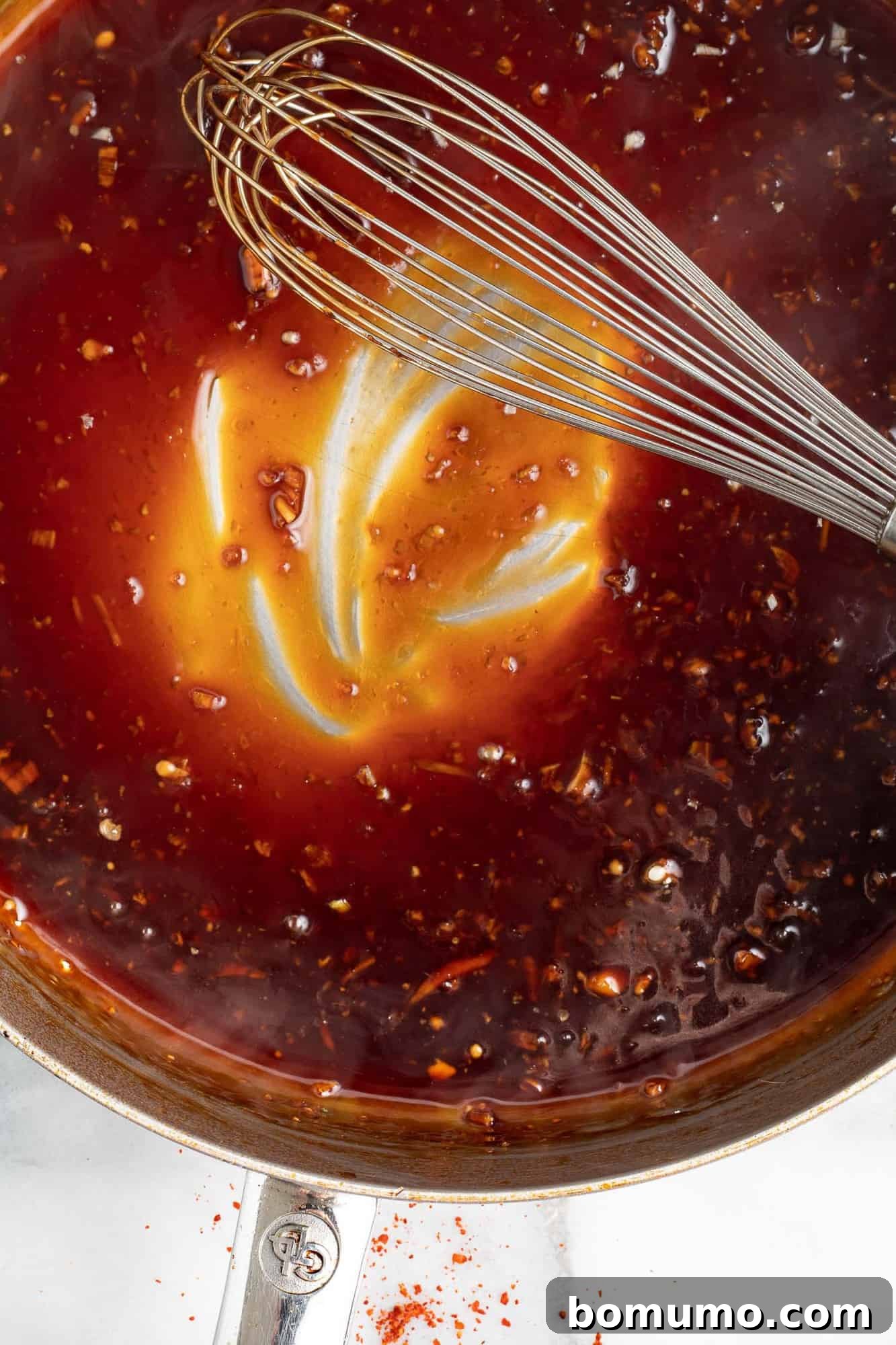 A close-up image of the finished sesame sauce in a small saucepan, showing its thick, glossy texture after being simmered.
