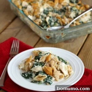 Chicken and kale casserole on white plate, with clear glass casserole pan in background.