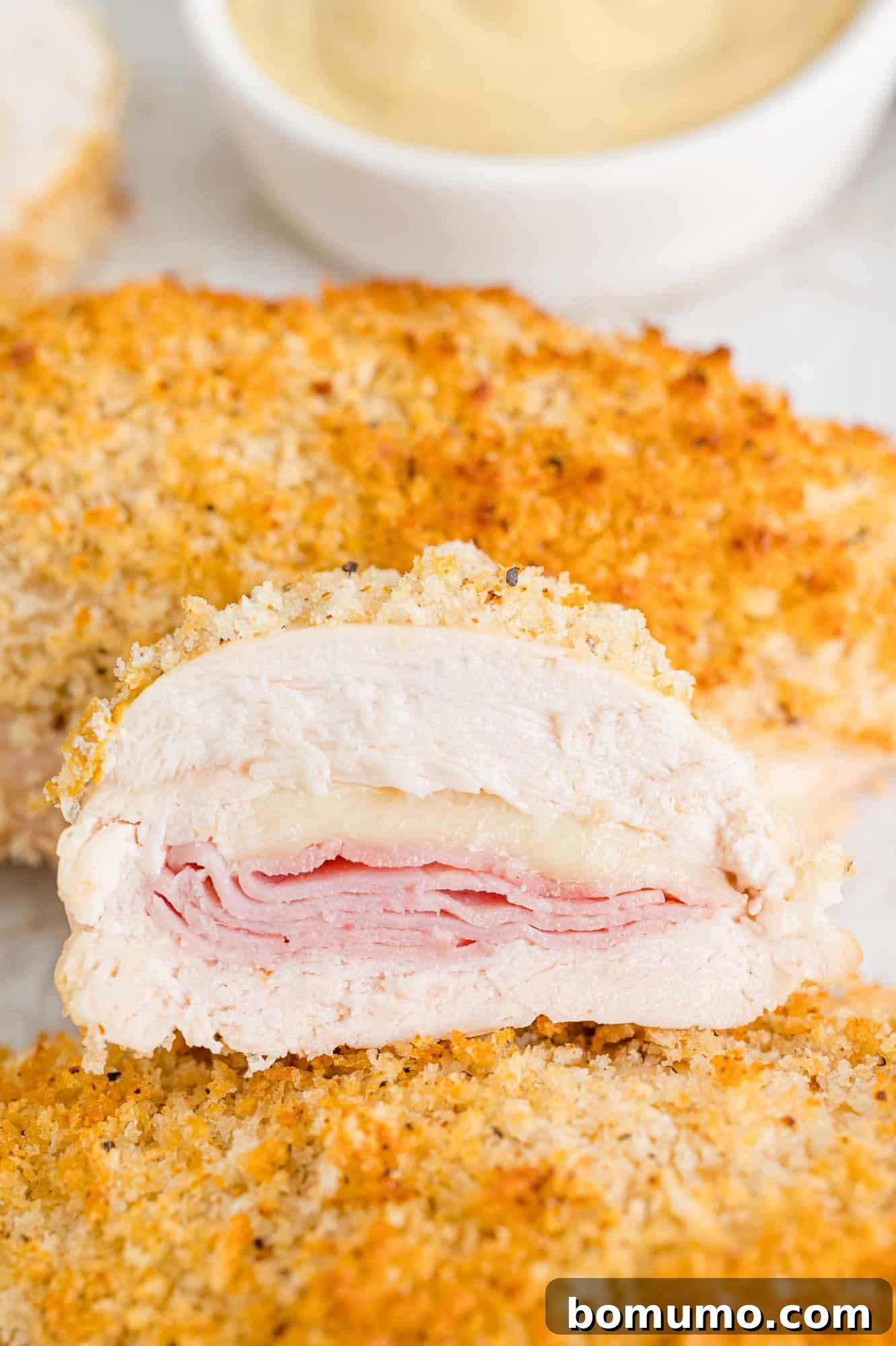 Baked chicken cordon bleu, cut in half to show filling of ham and Swiss cheese.