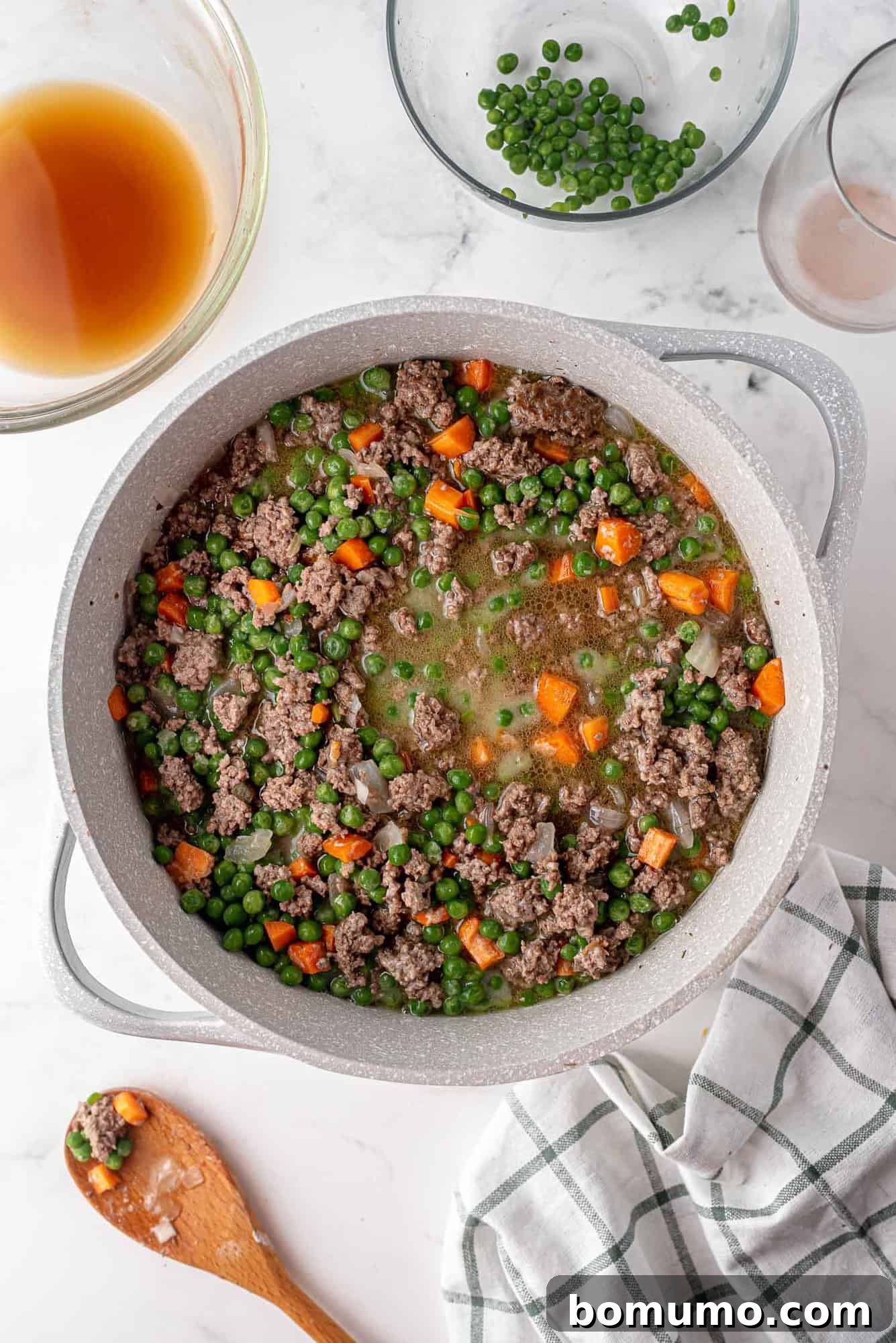 The rich and aromatic ground lamb, vegetable, and gravy mixture spread evenly in a large casserole dish, forming the flavorful and robust base of the shepherd's pie.