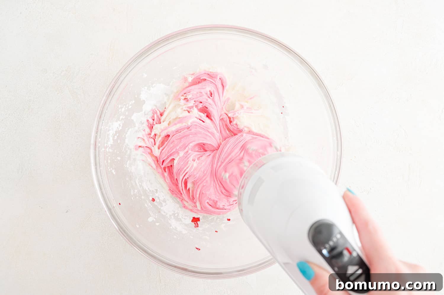 Frosting ingredients being mixed together with an electric mixer until light and fluffy.