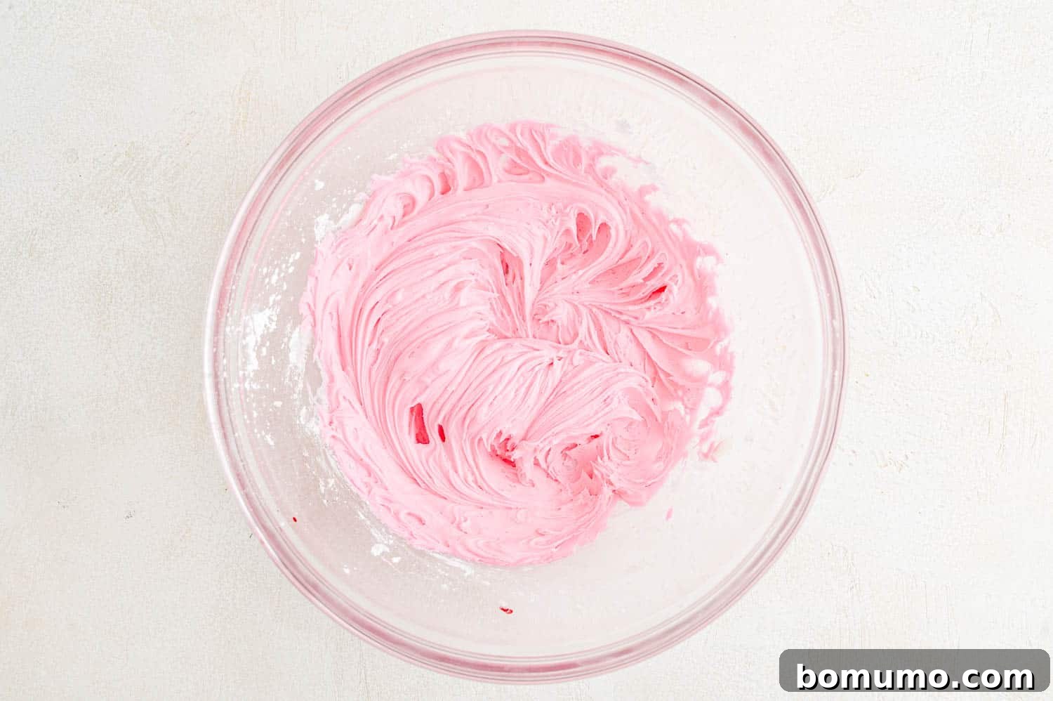 Beautiful pink buttercream frosting in a mixing bowl, perfectly fluffy and ready to spread.