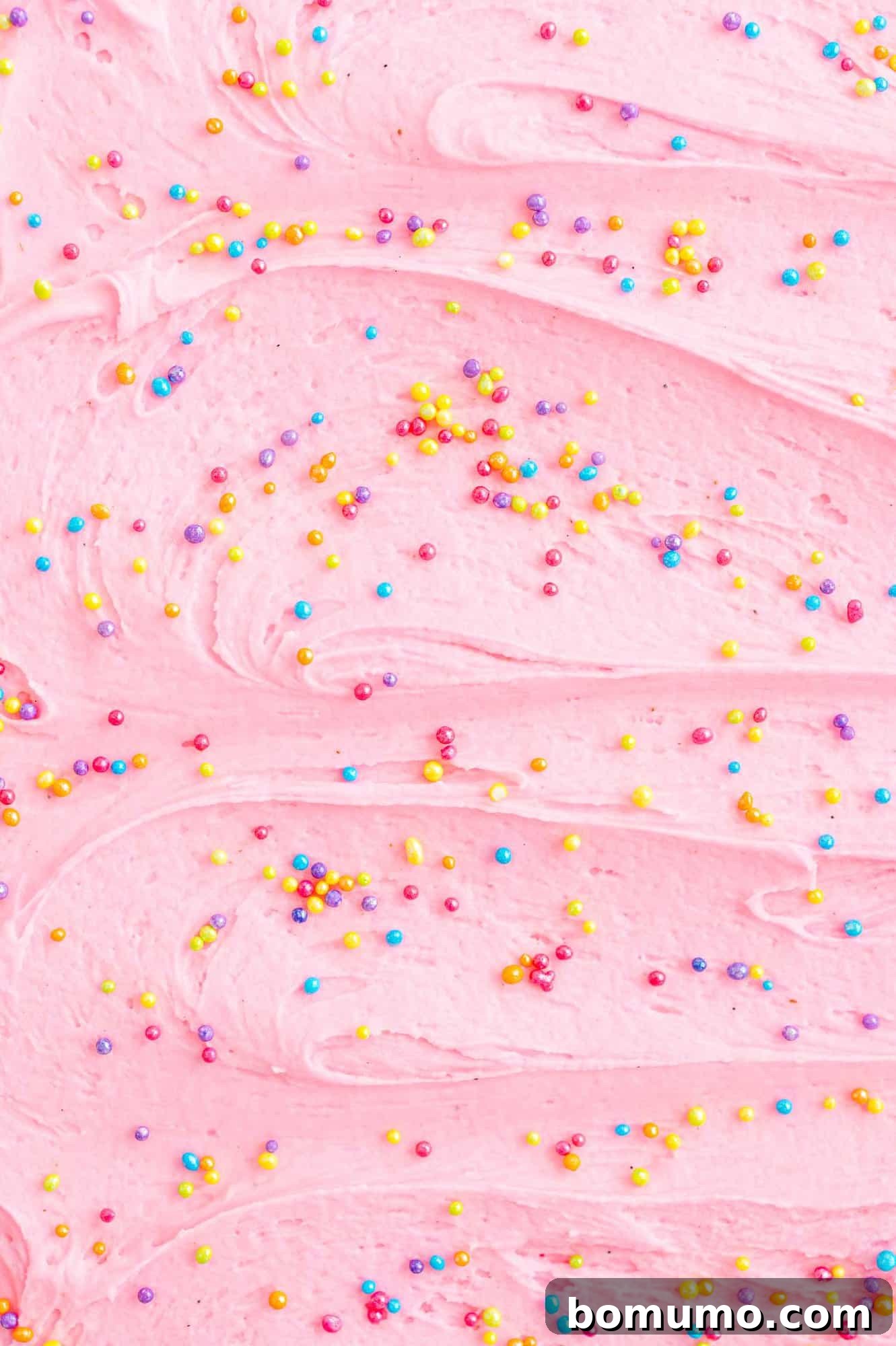 Light pink frosting with a generous scattering of multi-colored sprinkles, creating a festive look.