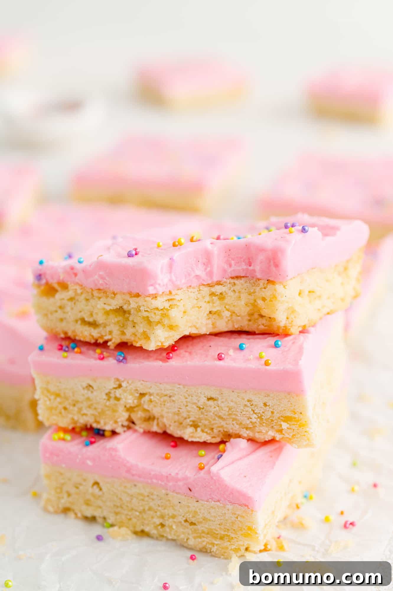 Three vanilla bean cookie bars with pink frosting, stacked elegantly on each other.