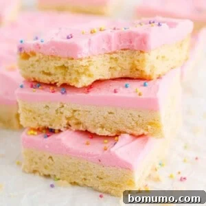Sugar cookie bars with pink frosting and sprinkles, stacked three high.