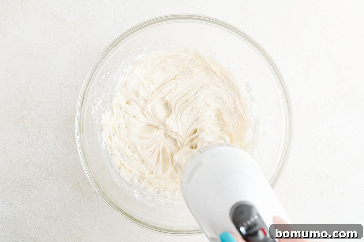 Butter and sugar being creamed together with an electric mixer, forming a light, fluffy mixture.